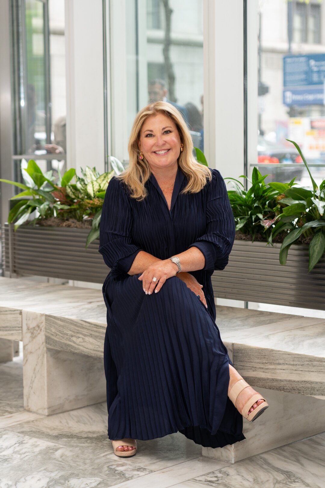 Beth McCormack in a navy dress, seated in a sunlit office